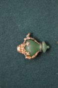 A yellow metal and jade pendant.