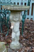 A reconstituted bird bath, the support modelled as a cherub.