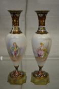 A pair of porcelain, champleve enamel and onyx pedestal vases, each decorated with a figure.