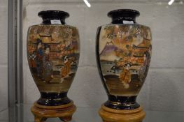 A pair of Japanese satsuma vases on stands.