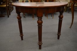 A mahogany demi-lune side table on turned and fluted legs.