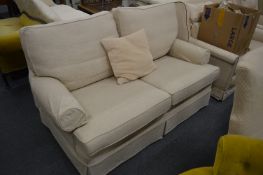 A cream upholstered two seater settee.