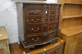 A reproduction mahogany serpentine fronted chest of drawers with brushing slide.