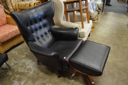 A stylish black vinyl revolving wing armchair with matching stool in the manner of Eames.