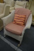 A lloyd loom chair with loose cushion and upholstered back panel.