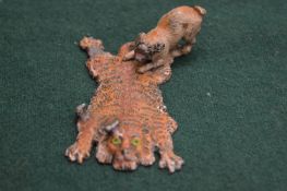 A small cold painted spelter group of a dog on a tiger skin rug.