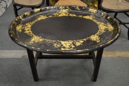 A Victorian gilt decorated papier mache oval tray on later stand.
