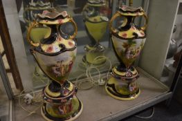 A pair of decorative urn shaped pottery pedestal vases on circular bases.
