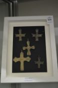 A group of bronze crosses, framed.