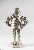 A STANDING CAST MICHELIN MAN on a circular tyre. 15ins high.