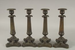 A GOOD SET OF FOUR REGENCY BRONZE CANDLESTICKS with triangular bases and claw feet. 10ins high.