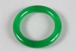 A CHINESE APPLE GREEN JADE BANGLE. 3.25ins diameter.