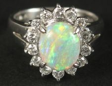 A PLATINUM RING set with a cabochon oval opal and a halo of RBC diamonds in a small ring size.