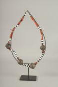 A SILVER AND HARDSTONE TRIBAL NECKLACE on a stand.