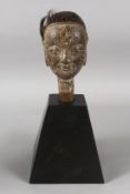 A CARVED AND PAINTED WOODEN MARIONETTE HEAD on a wooden stand. 5.5ins high.