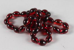 A STRING OF LARGE CHERRY AMBER BEADS. 34ins long.