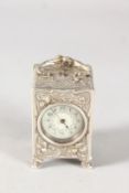 A SMALL GOLDSMITHS & SILVERSMITHS SILVER CLOCK with repousse decoration. 5ins high. London 1904.