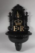 A BLACK PAINTED E.R. REPLICA WALL FOUNTAIN. 26ins high.