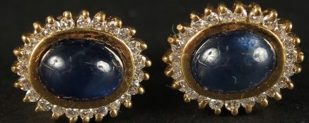 A PAIR OF 18CT YELLOW GOLD STUD EARRINGS set with oval cabochon sapphires within a surround of RBC