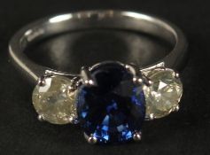 A CERTIFICATED 18CT WHITE GOLD SYNTHETIC SAPPHIRE AND DIAMOND TRILOGY RING. Oval sapphire 2.87ct.