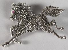 A SILVER MARCASITE RUBY EYE HORSE BROOCH.