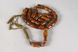 AN AMBER BEAD NECKLACE with tassel. 26ins long.