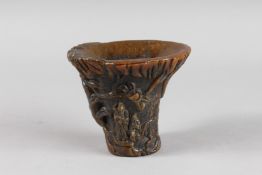 A CHINESE HORN LIBATION CUP carved with figures. 5ins high x 5.5ins wide.