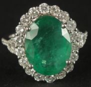 AN 18CT WHITE GOLD LARGE OVAL EMERALD AND RBC DIAMOND RING, with trapezoid and RBC diamond