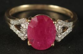 A 9CT YELLOW GOLD OVAL RUBY RING with diamonds set to the shoulders, boxed.