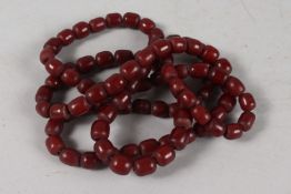 A SET OF RED BEAD - POSSIBLY BAKELITE OR CHERRY AMBER PRAYER BEADS.