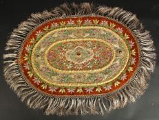 AN INDIAN EMBROIDERED OVAL TEXTILE WITH VARIOUS INSET STONES.