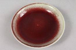 A CHINESE FLAMBE-STYLE RED GLAZE PORCELAIN DISH, with character mark to base, 19cm diameter.