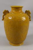 A LARGE CHINESE YELLOW GLAZE PORCELAIN KYLIN VASE, with carved decoration and twin ruyi handles,