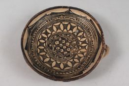A 19TH CENTURY NORTH AFRICAN PROBABLY ALGERIAN POTTERY DISH, 21cm diameter.