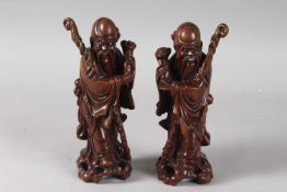 A PAIR OF 19TH CENTURY CHINESE CARVED HARDWOOD FIGURES, with inset eyes and teeth, 21cm high.