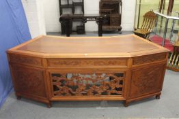 A LARGE CHINESE WOODEN DESK, with openwork front panel and seven drawers, 210cm wide, 77cm high,