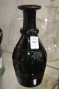 A dark green cut glass bottle or carafe.