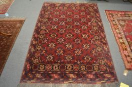 A Persian bokhara type rug, red ground with stylised decoration, 190cm x 130cm.
