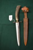 A hunting knife with horn handle and leather sheath.