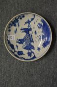 A Chinese blue and white dish decorated with figures seated in an exterior.