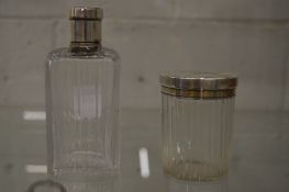 A pair of cut glass dressing table jars with white metal lids.