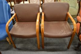 A pair of stylish brown leather upholstered armchairs.