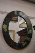 An oval mirror with floral painted frame.
