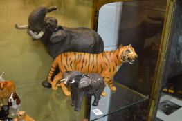 A large pottery model of a bull elephant another similar smaller elephant and a model of a tiger.