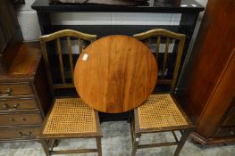 An ebonised open bookshelf, pair of cane seated chairs and a coffee table.