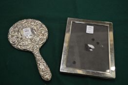 A silver backed hand brush and a plated photograph frame.
