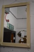 A small mirror with cream painted frame.
