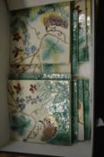 A collection of glazed square shaped tiles decorated with birds and insects.