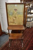 A 19th century mahogany fire screen with shelves, the panel embroidered with silks depicting a