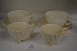 A pair of Belleek shell shaped cups with green stamp together with a pair of similar cups and